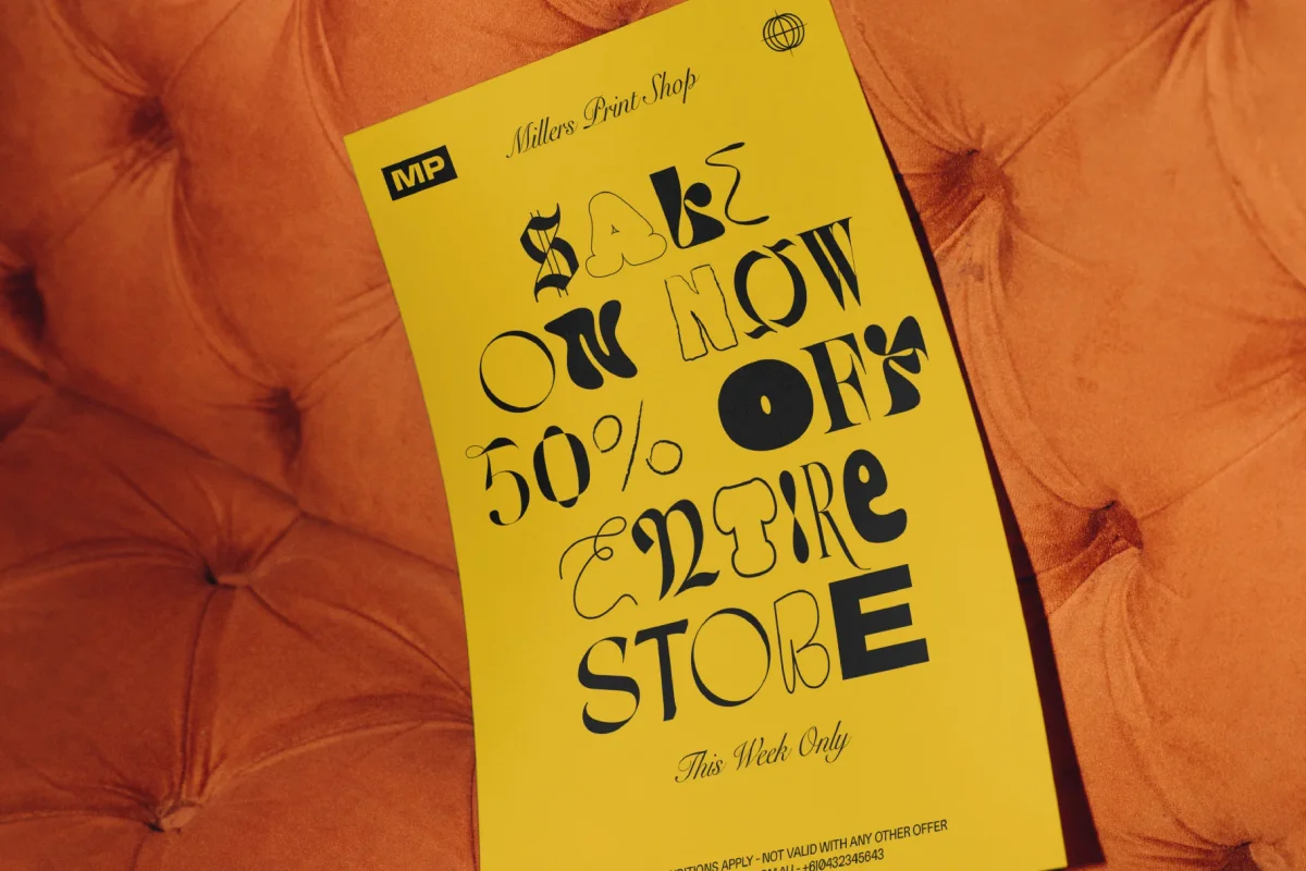 Yellow flyer with the text "SALE ON NOW 50% OFF ENTIRE STORE" in a mix of Alpha Punk font styles, placed on an orange sofa.