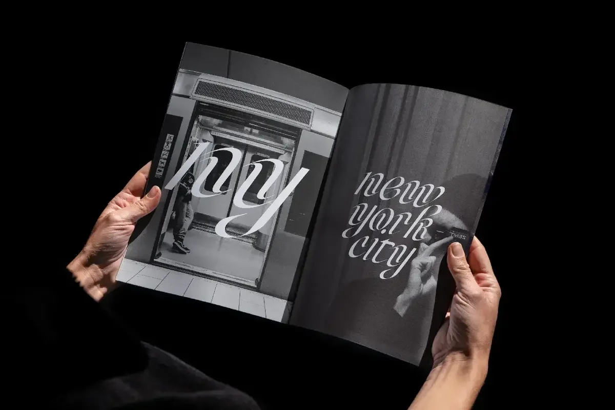 Hands holding a magazine featuring stylish black-and-white typography with the words NY and New York City.