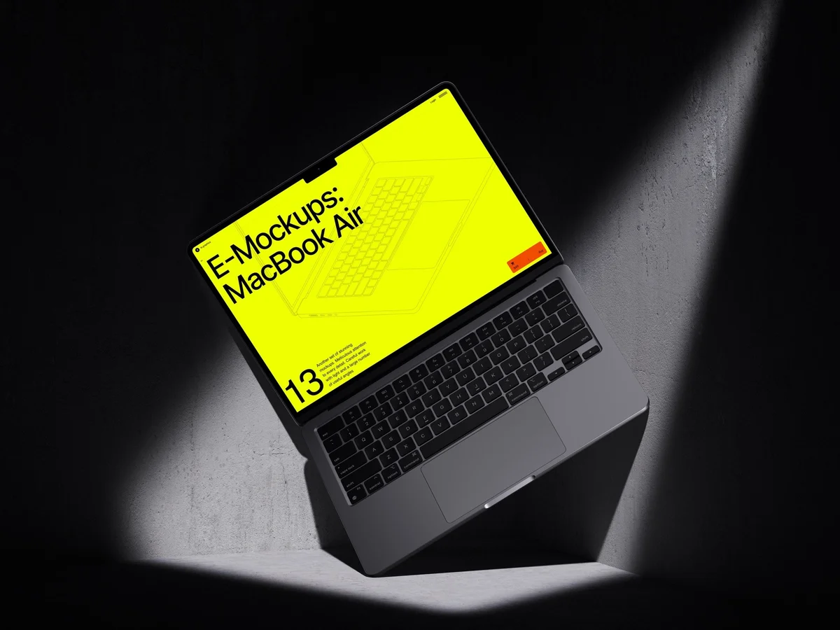 A MacBook Air with a vibrant yellow screen is positioned at an angle on a dark, textured surface under a spotlight, making it ideal for showcasing bold and energetic web and app design presentations.