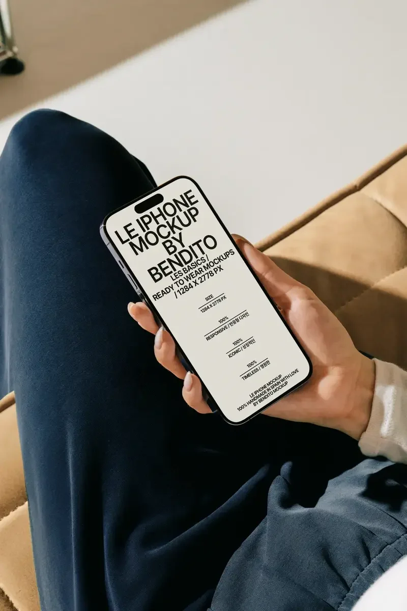 A person on a sofa, holding an iPhone displaying a Bendito Mockup screen with bold text. Perfect for UX and UI design presentations.