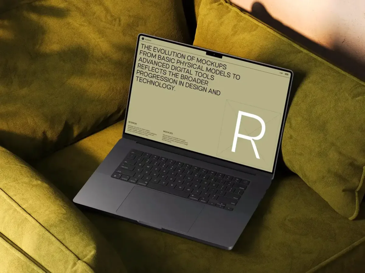 A MacBook on a green, velvety couch, displaying a website mockup with bold black text on a beige screen, emphasizing the evolution of mockups and their role in design progression.