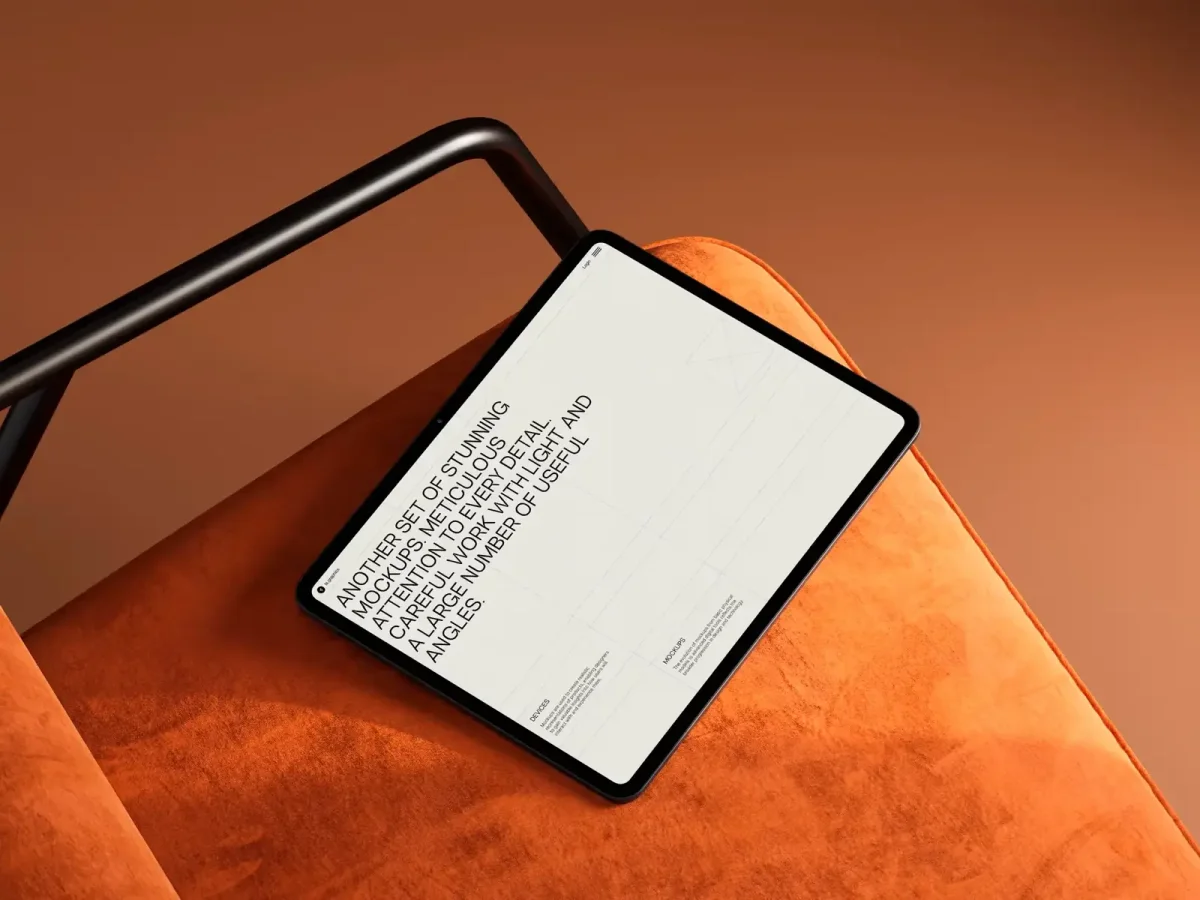 An iPad mockup lying on an orange cushioned chair, showcasing a minimalist website interface with text, emphasizing interior and design mockups.