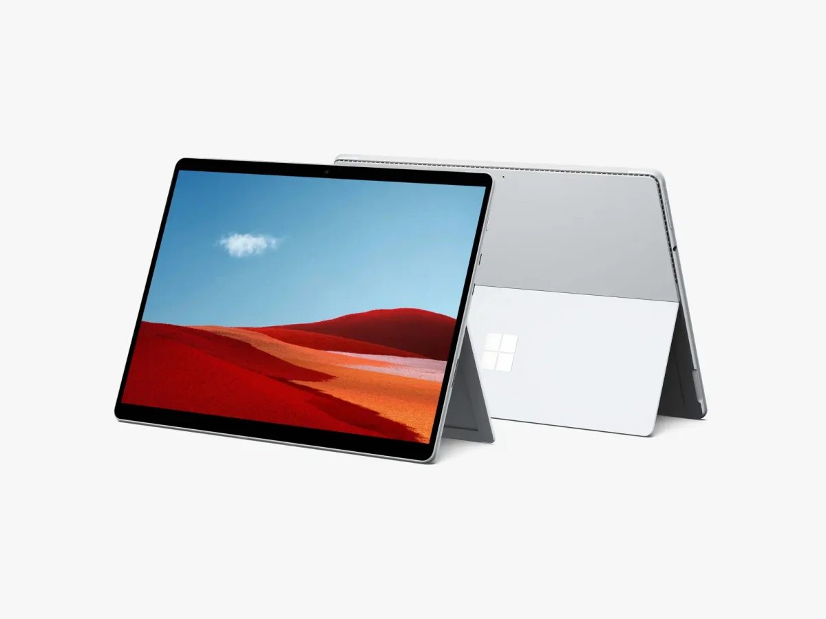 Two Surface Pro devices back-to-back, one displaying the desert landscape while the other shows the back panel with the Microsoft logo.